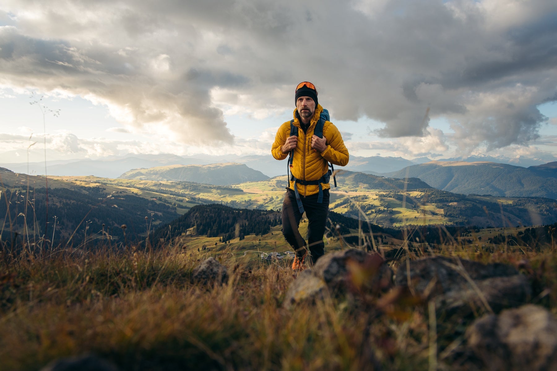 Wanderer auf einem felsigen Grat mit weitem Blick über die Alpen